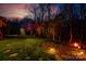 Landscaped backyard at dusk, featuring colorful illuminated trees and lush lawn at 4232 Belle Meade Cir, Belmont, NC 28012