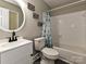 Bright bathroom with a round mirror, modern sink, a toilet, and a shower-tub combo with curtain at 4522 Chuckwood Dr, Mint Hill, NC 28227