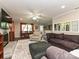 Open living room with a brick fireplace, ceiling fan, views to a dining area, bar, and backyard at 4522 Chuckwood Dr, Mint Hill, NC 28227