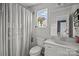A clean bathroom with a shower-tub combo, toilet, and vanity with flowers on the windowsill at 5030 Lily Pond Cir, Waxhaw, NC 28173