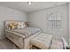 A neutral bedroom featuring a beautifully styled bed, upholstered bench, and a bright window at 5030 Lily Pond Cir, Waxhaw, NC 28173