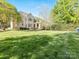 Expansive backyard featuring well-manicured lawn, lush trees, and covered patio at 5811 Old Well House Rd, Charlotte, NC 28226