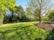 Large grassy backyard surrounded by mature trees and landscaping at 5811 Old Well House Rd, Charlotte, NC 28226