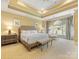 Spacious main bedroom featuring tray ceilings, a sitting area, and an arched window with curtains at 5811 Old Well House Rd, Charlotte, NC 28226