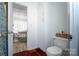 This bathroom features a toilet, cabinets, and a doorway leading to an airy bedroom with a bed at 6199 Timberlane Ter, Hickory, NC 28601
