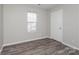 This bedroom features neutral paint, wood-look flooring, and a window for natural light at 7830 Lobilia Ln, Charlotte, NC 28214