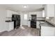 Modern kitchen featuring black appliances, white cabinetry, and luxury vinyl plank flooring at 7830 Lobilia Ln, Charlotte, NC 28214