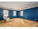 A large bedroom featuring carpeted floors, blue walls, and a seating area in front of three large windows at 1008 High Wedge Rd, Shelby, NC 28152