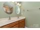 Bathroom with double sinks, wood vanity, two round mirrors, and tiled shower at 1026 Eagles Nest Ln, Fort Mill, SC 29707