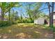 Backyard with lush green grass, mature trees, wooden fence, and a storage shed at 1631 Fulton Ave, Charlotte, NC 28205