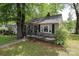 Gray cottage style home with front porch surrounded by mature trees and a green lawn at 1900 Union St, Charlotte, NC 28205