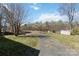 Large backyard with a driveway leading to a distant shed, surrounded by mature trees at 1923 Tracy Ct, Fort Mill, SC 29708