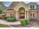 Elegant brick home showcasing an arched entryway with white columns and a custom wood front door at 2045 Driftwood Cir, Fort Mill, SC 29708