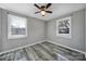 A bright bedroom features two windows, gray walls and modern ceiling fan and grey wood-look flooring at 2301 Shamrock Dr, Charlotte, NC 28205