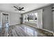 Bright living room featuring hardwood floors, neutral paint, a ceiling fan, and large bay windows at 2301 Shamrock Dr, Charlotte, NC 28205