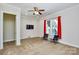 A neutral living room with a ceiling fan, TV, red curtained window and two stylish chairs on carpet at 341 Canvasback Rd, Mooresville, NC 28117