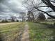 A long gravel driveway lead to a house on a large lot with mature trees in the yard at 4349 Roberta Rd, Concord, NC 28027