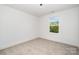 A bright, carpeted bedroom featuring a single window and neutral decor at 5108 Potter Rd, Matthews, NC 28104