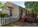 View of the back of a cozy home with a small deck, a white picket fence, and tidy landscaping at 602 S Church St, Lowell, NC 28098