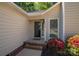 Inviting front entrance with storm door and landscaped bed with vibrant red flowers at 602 S Church St, Lowell, NC 28098