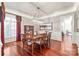 Formal dining room with hardwood floors, chandelier, and wainscoting with a large picture window and red curtains at 7308 Amberwood Ct, Charlotte, NC 28226