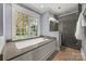 Bright bathroom featuring a soaking tub beneath a large window and a walk-in shower at 7700 Red Oak Ln, Charlotte, NC 28226