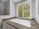Elegant bathroom with a soaking tub situated beneath a large window offering tranquil views at 7700 Red Oak Ln, Charlotte, NC 28226