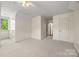 Spacious bedroom featuring neutral carpet, a window, and access to the hallway at 7700 Red Oak Ln, Charlotte, NC 28226