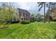 Well-manicured front yard of a brick home with lush green grass and mature trees at 7700 Red Oak Ln, Charlotte, NC 28226