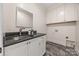 Well-lit laundry room with a dark countertop, white cabinets, and modern fixtures at 7700 Red Oak Ln, Charlotte, NC 28226