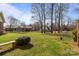 Expansive backyard with mature trees, green grass, and a charming bench at 8260 Graham Rd, Denver, NC 28037