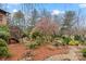 Beautiful backyard with a manicured garden featuring mature trees, mulch beds, and a stone pathway, creating a serene outdoor space at 106 Brookwood Ln, Taylorsville, NC 28681