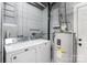 Well-lit laundry room with washer, dryer, and water heater against gray brick wall at 106 Brookwood Ln, Taylorsville, NC 28681