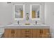 A bright bathroom with double sinks, wood cabinets, modern fixtures, and LED illuminated mirrors at 1300 Queens Rd # 408, Charlotte, NC 28207