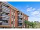 Brick condo building exterior with balconies and palm trees set against a bright blue sky at 1300 Queens Rd # 408, Charlotte, NC 28207