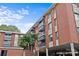 An exterior view of the multi-story red brick condo building on a beautiful day with palm trees at 1300 Queens Rd # 408, Charlotte, NC 28207