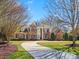 Stately brick home featuring a circular driveway, white columns, and lush landscaping at 1511 Churchill Downs Dr, Waxhaw, NC 28173