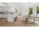 Open concept kitchen features white cabinets, island with seating, and a view of the adjacent dining and living areas at 1511 Churchill Downs Dr, Waxhaw, NC 28173