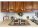 Close-up of the stainless steel kitchen sink with wooden cabinets, complemented by decorative plants and wreath at 167 Holly Harbor Trl # 169/170, Mount Gilead, NC 27306