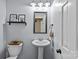 Cozy powder room features a sleek pedestal sink, stylish mirror, and decorative shelving for added storage at 2016 Monaghan Ct, Matthews, NC 28105