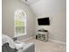 Bedroom featuring a gray upholstered chair, large window, and mounted TV at 3100 Stanway Ct, Waxhaw, NC 28173