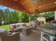 Inviting covered patio with stone accents, wood ceiling, outdoor kitchen and comfortable seating with a landscaped backyard view at 3100 Stanway Ct, Waxhaw, NC 28173