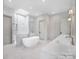 Bright bathroom with a modern tub, double vanity, and glass-enclosed shower with marble tiling and a skylight at 3212 Willow Oak Rd, Charlotte, NC 28209