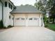 Attached two-car garage featuring white doors, decorative lighting, and natural wood accents on a manicured lawn at 3212 Willow Oak Rd, Charlotte, NC 28209