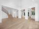 Open-concept living room with light wood floors, white walls, staircase, and a modern chandelier at 3212 Willow Oak Rd, Charlotte, NC 28209