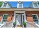 Close-up of the brick home's entry featuring a decorated front door with sconces and manicured potted plants at 3412 Country Club Dr, Gastonia, NC 28056