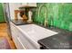 Close-up of a white farmhouse sink with a gold faucet, complemented by dark countertops and green tile at 3726 Providence Rd, Charlotte, NC 28211