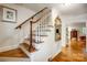 Classic staircase with hardwood steps, white risers, and wooden handrail, bathed in natural light from the nearby windows at 3726 Providence Rd, Charlotte, NC 28211