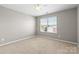 A vacant bedroom with neutral carpet and a window offering natural light at 5827 Eleanor Rigby Rd, Charlotte, NC 28278