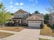 Beautiful two-story home with an attached garage, a well-manicured lawn, and a classic brick facade at 5827 Eleanor Rigby Rd, Charlotte, NC 28278